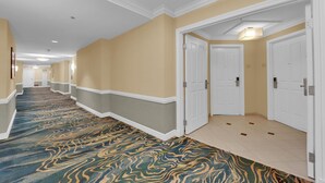 A hotel corridor with a patterned carpet, cream-colored walls, and white doors. - Mirai MGM (Las Vegas)
