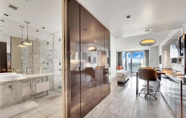 Une chambre d’hôtel moderne dotée d’une grande salle de bain, d’un coin cuisine et d’un espace salon avec vue.