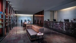 A modern lobby with a reception desk, seating area, and glass display cases. - Luxurious Sub-penthouse Studio Balcony Access (Las Vegas)