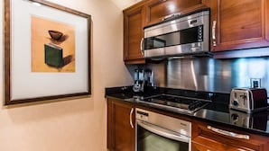 A kitchen with wooden cabinets, a stainless steel microwave, a toaster, and a dishwasher. - MGM Signature 1BR Balcony 06721 (Las Vegas)