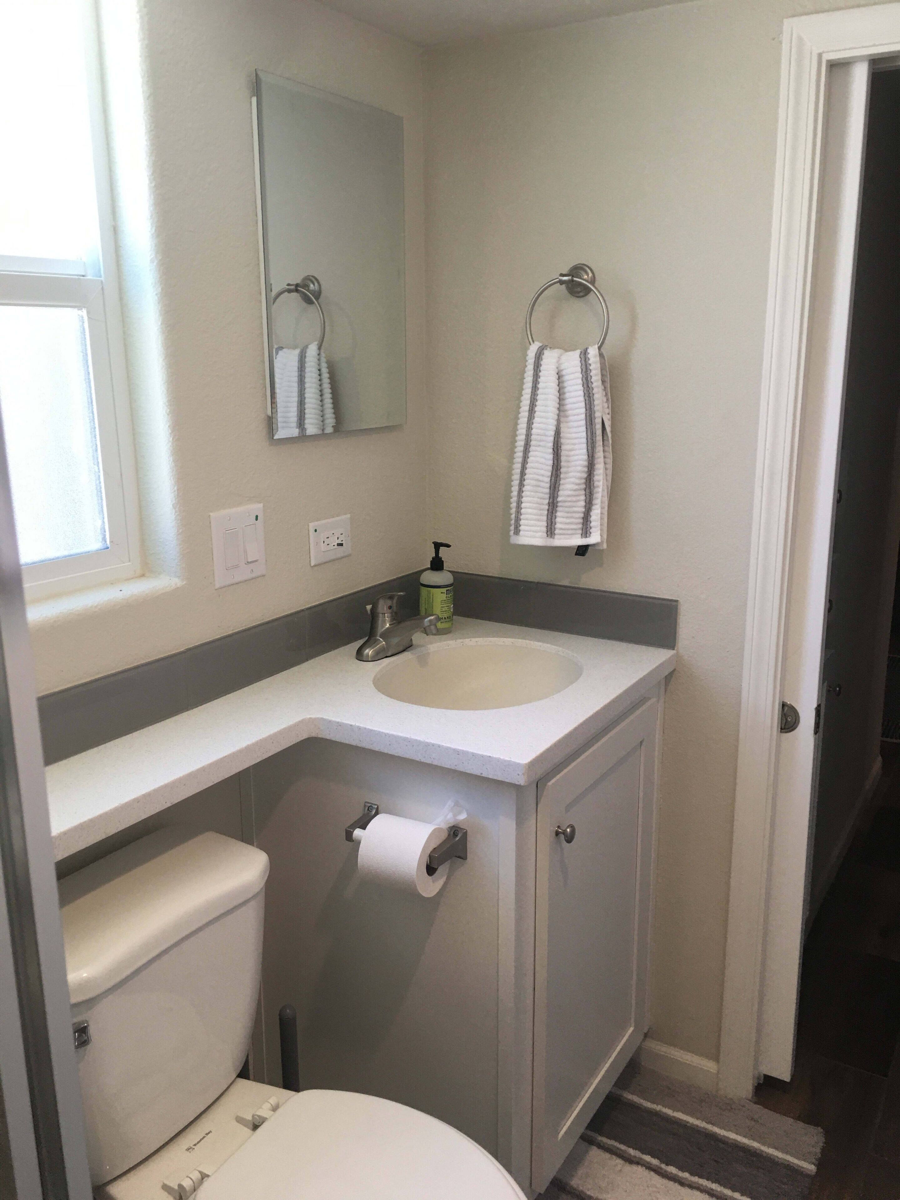 A bathroom with a toilet, sink, and mirror.