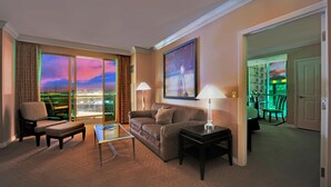 Habitación de hotel con un amplio ventanal que ofrece vistas a la ciudad, un sofá, una mesa de centro y una lámpara.