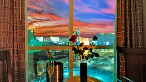 Una habitación con un ventanal que ofrece vistas a un horizonte urbano al atardecer.