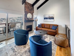 Un salon moderne avec une cheminée, un canapé et deux fauteuils bleus.
