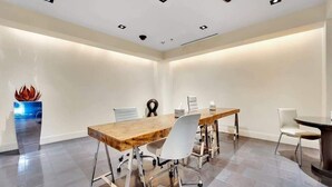 A conference room with a long wooden table, white chairs, and a dark round table. - Luxury 1BR Palms Strip View + Balcony Access 37322 (Las Vegas)