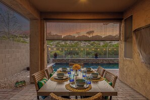 An outdoor dining area with a pool, wicker furniture, and a view of a desert landscape. - 119th Sun City (Sun City)