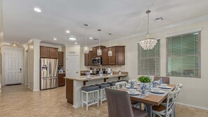 A modern kitchen with granite countertops, stainless steel appliances, and pendant lighting. - 119th Sun City (Sun City)