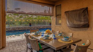 A dining area with a pool view, wicker chairs, and a table set with blue bowls and glasses. - 119th Sun City (Sun City)