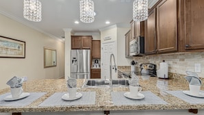A modern kitchen with granite countertops, stainless steel appliances, and wooden cabinets. - 119th Sun City (Sun City)