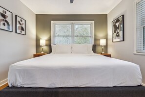 A large bed with white linens, two bedside lamps, and a window with blinds. - 425 Plantation Road SW, Smyrna (Smyrna)