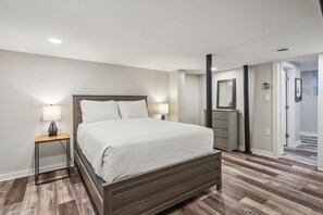 A bedroom with a wooden bed, two bedside tables with lamps, a dresser, and a mirror on the wall. - 425 Plantation Road SW, Smyrna (Smyrna)