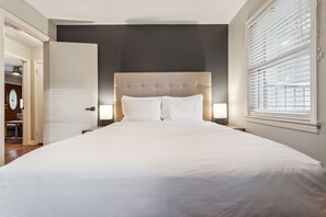 A neatly made bed with white linens, a tufted headboard, and two bedside lamps. - 425 Plantation Road SW, Smyrna (Smyrna)
