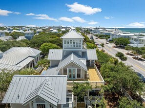 A coastal residential area with houses featuring gabled roofs and a prominent two-story house with a balcony. - Four by the Shore (Santa Rosa Beach)