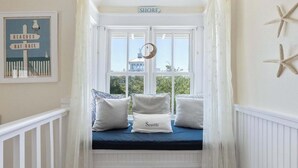 A bay window with a view of the sea, a sign reading "BEACHES RAT RACE", and a cushion labeled "Seaside". - Four by the Shore (Santa Rosa Beach)