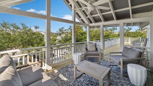 A covered outdoor area with a ceiling fan, seating with cushions, and a patterned rug. - Four by the Shore (Santa Rosa Beach)