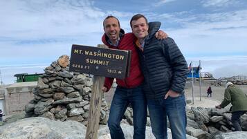 Two people standing next to a sign that reads 'MT. WASHINGTON SUMMIT 6288 FT 1917 M'.