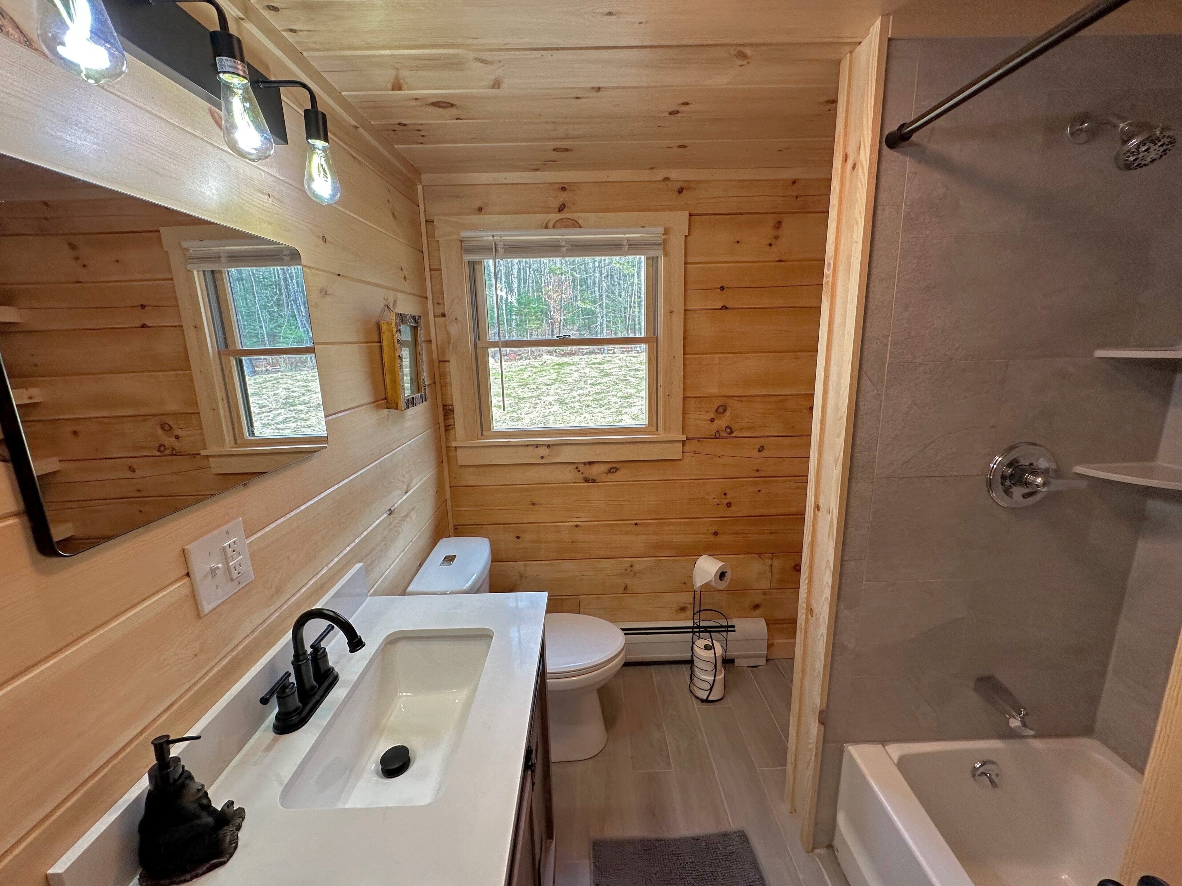 A wooden cabin bathroom with a sink, toilet, and shower.