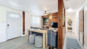 A compact living space with a dining area, a sofa, a TV, and a ceiling fan. - Modern 3 Bedroom Retreat With Pool & Fire Pit (Largo)