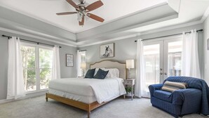 Une chambre à coucher avec un lit, une chaise, un ventilateur de plafond et une fenêtre.