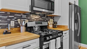 Una cocina moderna con microondas de acero inoxidable, estufa a gas y refrigerador.