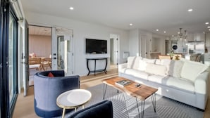 Een moderne woonkamer met een witte bank, een blauwe fauteuil en een salontafel.