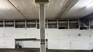 Een ondergrondse parkeergarage met betonnen vloeren en muren, aangegeven parkeerplaatsen en een centrale pilaar met het nummer '68'.