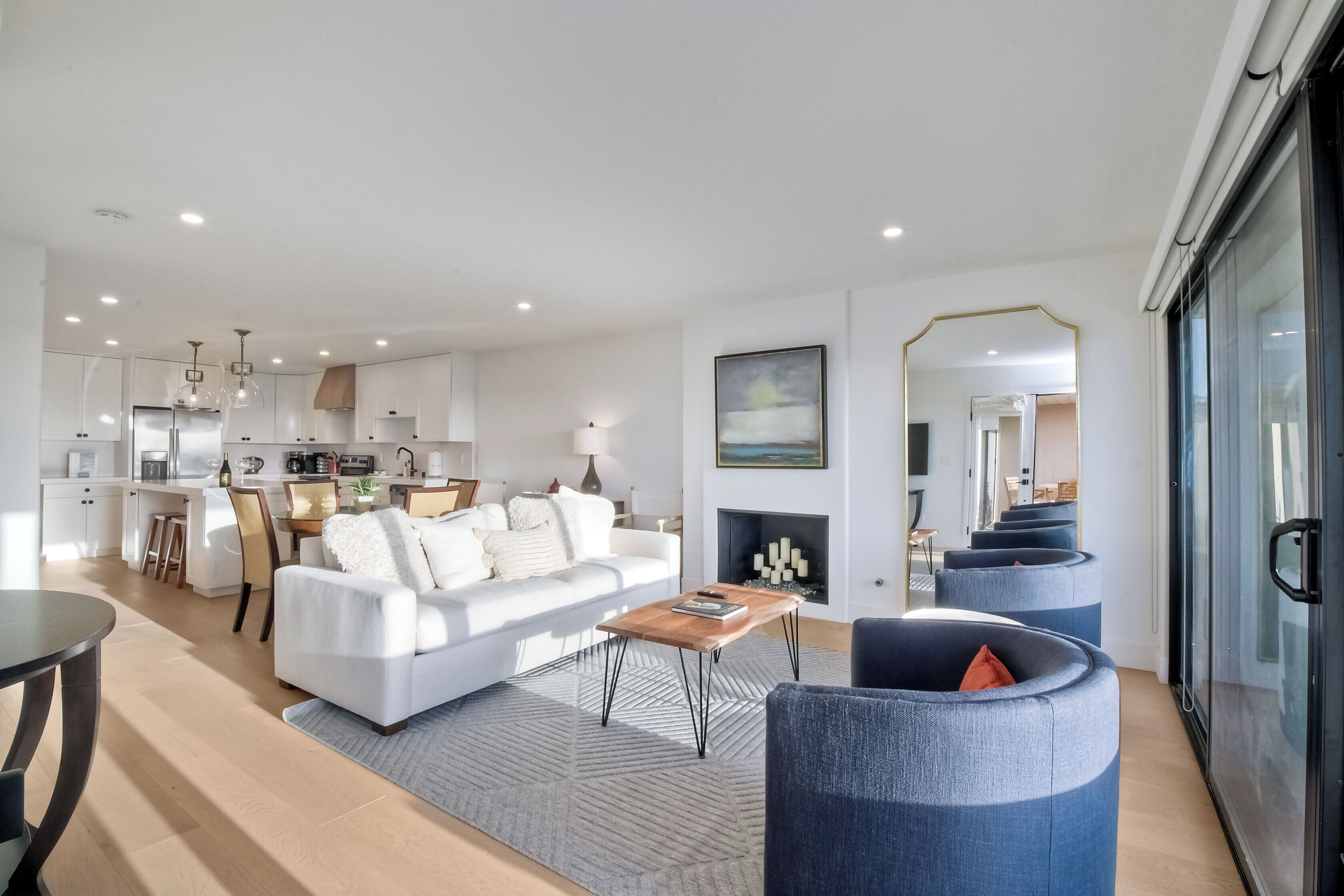 A modern living room with a white sofa, a coffee table, and a fireplace.
