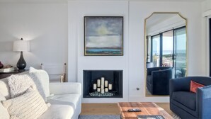 Een moderne woonkamer met een open haard, een grote spiegel en uitzicht op de omgeving.