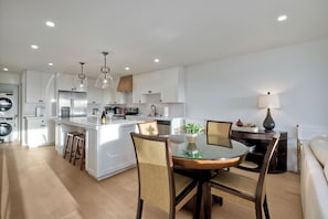 Une cuisine moderne avec des meubles blancs, un îlot central et des luminaires suspendus.