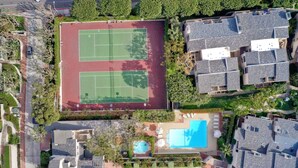 Luchtbeeld van een woongebied met twee tennisbanen, een zwembad en meerdere huizen.