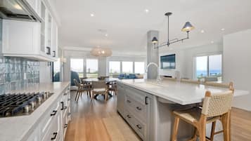 A modern kitchen with a large island, white cabinetry, and a view to the outdoors.