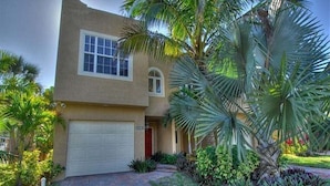 A two-story house with a garage, palm trees, and a brick pathway. - Avenida De Cortez (Siesta Key)