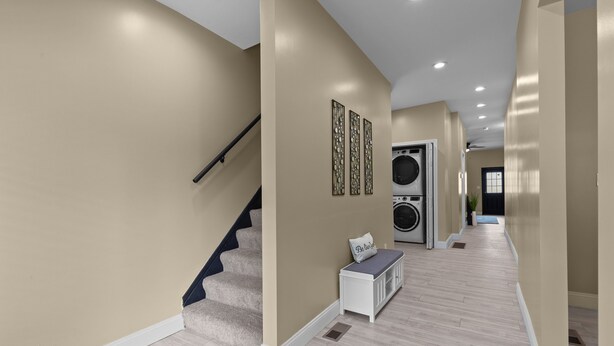 A hallway with a staircase, a bench, and a washing machine. - Red Brick Hideaway (St. Louis)