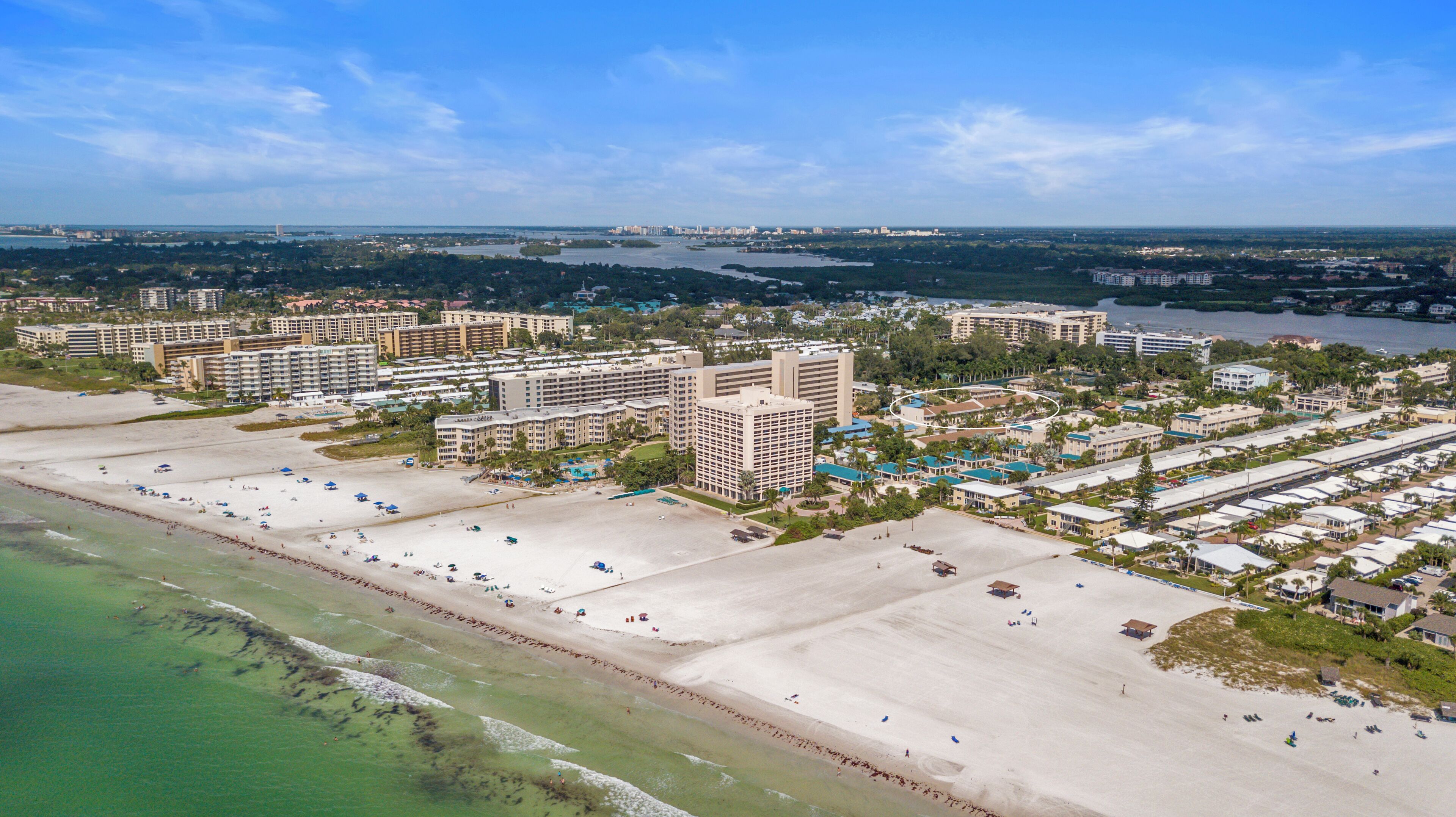 A coastal resort area with multiple high-rise buildings, a sandy beach, and a marina.