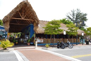 A restaurant with a thatched roof and outdoor seating area. - Jamaica Royale (Siesta Key)