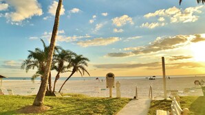 A beach path with palm trees, a sign, and beach chairs. - Jamaica Royale (Siesta Key)