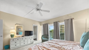 A bedroom with a bed, dresser, television, and a ceiling fan. - Jamaica Royale (Siesta Key)