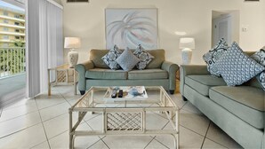 A living room with two sofas, a glass coffee table, and a painting on the wall. - Jamaica Royale (Siesta Key)