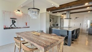 A modern kitchen with a wooden dining table, chairs, and a chandelier. - Sandy Cove - Unit 401 (Siesta Key)