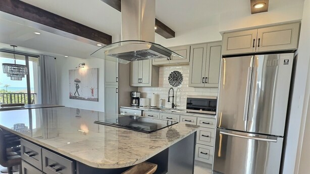 A modern kitchen with a large island, stainless steel appliances, and a view of the ocean. - Sandy Cove - Unit 401 (Siesta Key)