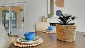 Un comedor con mesa de madera, cuencos azules, una cesta tejida y un cuadro abstracto colgado en la pared.