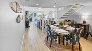 A dining area with a round table, chairs, and a staircase leading to an upper level. - Bayside Pointe - 1232 (Siesta Key)
