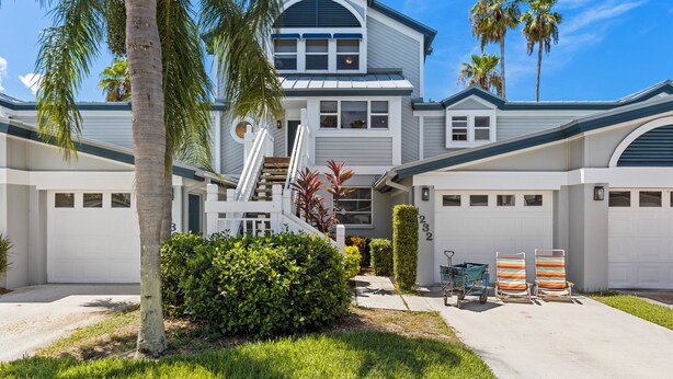 A two-story house with a garage, a covered porch, and a staircase leading to the second floor. - Bayside Pointe - 1232 (Siesta Key)