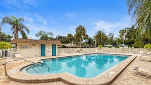A swimming pool with a tiled deck, lounge chairs, and palm trees in the background. - Siesta Beach House 203 Sunny Daze (Siesta Key)