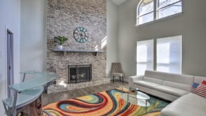 A modern living room with a stone fireplace, a glass coffee table, a white sofa, and a colorful rug. - Texas - Justin 7 (Stafford)