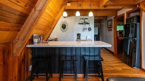 Eine Küche mit Holzbalkendecke, einer zentralen Kochinsel mit Barhocker und einem Kühlschrank.
