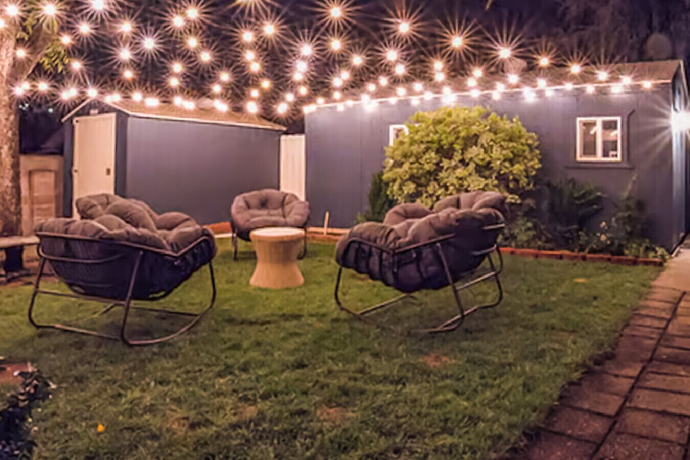 A patio with two rocking chairs, a small round table, and a hedge.