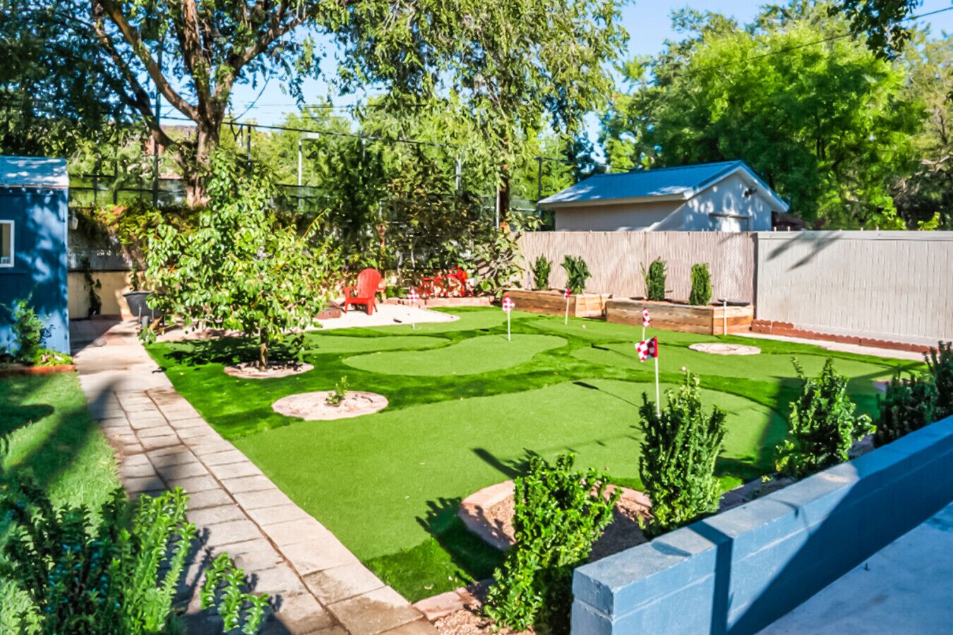 A well-maintained backyard with a lawn, a red chair, and a small garden area.
