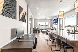 Une cuisine moderne dotée d’un grand îlot central, de tabourets de bar et d’une grande fenêtre offrant une vue sur la ville.