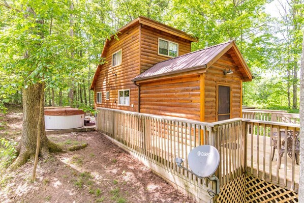 A wooden cabin with a deck, surrounded by trees. - Gorgeous View Cabin - in Red River Gorge, KY (Slade)